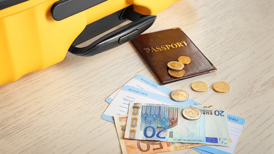 A passport and money lay next to a suitcase
