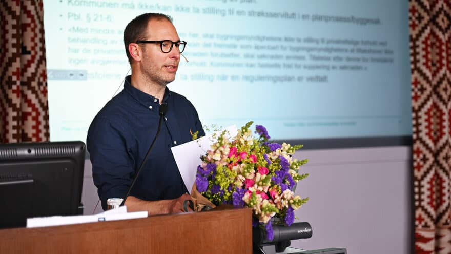 Fredrik Holth med blomsterbukett, stående ved katetet