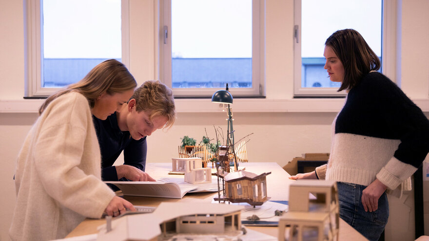 Studenter på NMBUs studieprogram Byggeteknikk og arkitektur jobber med modeller av hytter.
