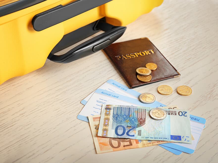 A passport and money lay next to a suitcase